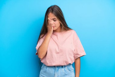 Kafkasyalı genç bir kadın mavi arka planda izole edilmiş, baş ağrısı var.