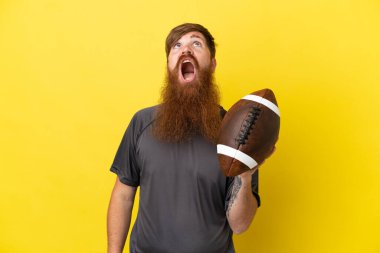 Kızıl saçlı beyaz adam sarı arka planda ragbi oynuyor.