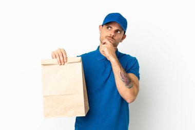 Brezilyalı beyaz arka planda izole edilmiş bir paket yiyecek alıyor ve yukarı bakıyor.