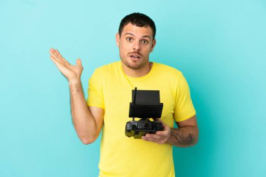 İzole edilmiş mavi arkaplan üzerinde uzaktan kumandalı Brezilyalı bir adam el kaldırırken şüphe duyuyor