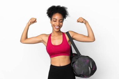 Spor çantalı genç Afro-Amerikan kadın mavi arka planda izole edilmiş güçlü bir jest yapıyor.