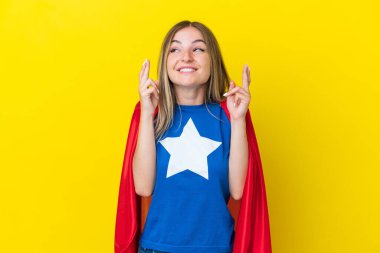 Süper Kahraman Rumen kadın sarı arka planda izole edilmiş, parmakları çapraz
