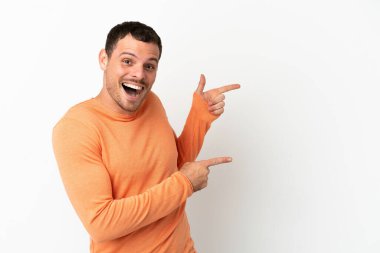 İzole edilmiş beyaz arka planı olan Brezilyalı adam şaşırmış ve işaret ediyor.
