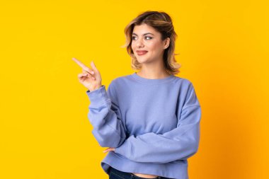 Sarı arka planda izole edilmiş genç bir Rus kadını işaret ediyor.