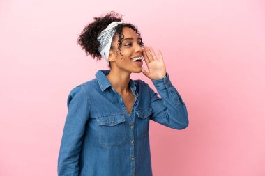 Pembe arka planda izole edilmiş genç Latin kadın ağzı sonuna kadar açık bağırıyor.