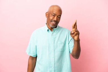 Kübalı son sınıf öğrencisi pembe arka planda izole edilmiş, şans diliyor ve en iyisini diliyor.