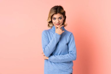 Pembe arka planda izole edilmiş genç Rus kadın yukarı bakarken bir fikir düşünüyor.