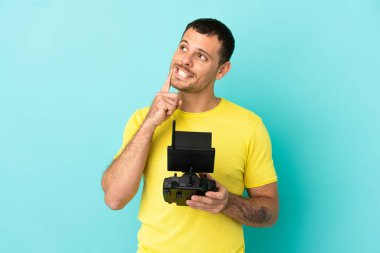 Brezilyalı bir adam uzaktan kumandayla mavi arkaplanı kontrol ediyor.