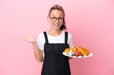Restoran garsonu elinde waffle tutan Rus kız pembe arka planda şok olmuş bir yüz ifadesiyle izole edilmiş.