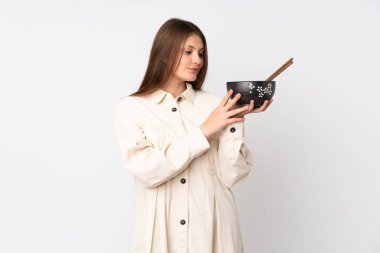 Beyaz arka planda, elinde çubuklarla elinde bir kase şehriye tutarken mutlu bir ifadeyle izole edilmiş beyaz bir kız.