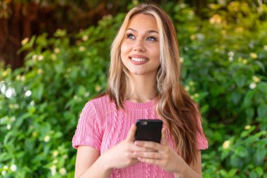 Dışarıda cep telefonu kullanan güzel bir kadın var.