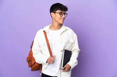 İzole edilmiş mor arka plan görünümlü genç bir öğrenci.