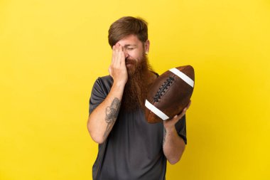 Kızıl saçlı beyaz adam sarı arka planda ragbi oynuyor.