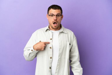 İzole edilmiş mor arka planı olan Brezilyalı bir adam kendini işaret ediyor.