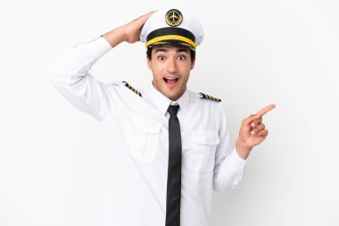 İzole edilmiş beyaz arka plan üzerinde uçak pilotu şaşırdı ve parmağını yana çevirdi.