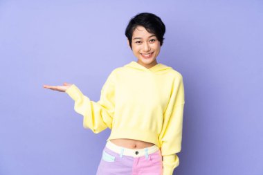 Mor arka planda kısa saçlı genç Vietnamlı kadın bir ilan vermek için avucunun içinde hayali bir fotokopi makinesi tutuyor.