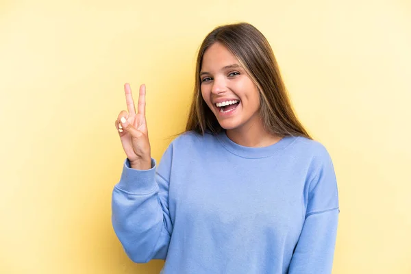 Jonge Kaukasische Vrouw Geïsoleerd Gele Achtergrond Glimlachen Tonen Overwinning Teken — Stockfoto