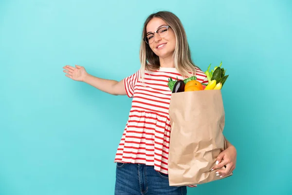 Jonge Vrouw Met Een Boodschappentas Geïsoleerd Blauwe Achtergrond Handen Naar — Stockfoto