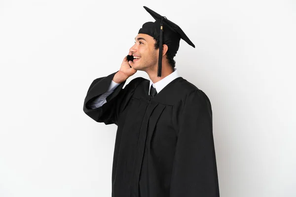 Fiatal Egyetemi Diplomás Elszigetelt Fehér Háttér Miközben Egy Beszélgetést Mobiltelefon — Stock Fotó