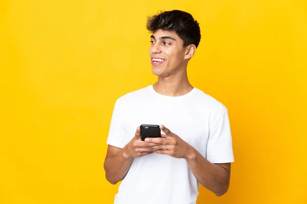 Sarı Arka Plan Izole Edilmiş Genç Adam Cep Telefonu Kullanıyor — Stok fotoğraf