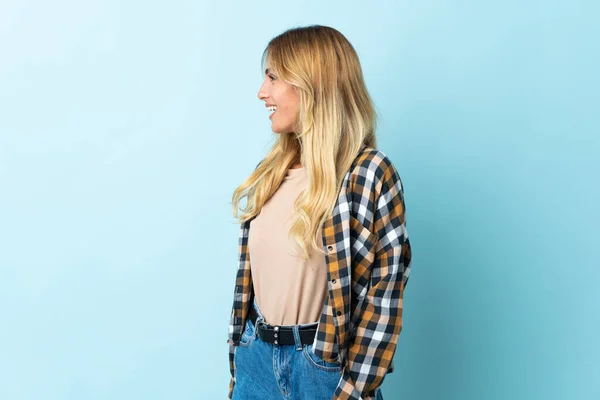 Joven Rubia Uruguaya Aislada Sobre Fondo Azul Riendo Posición Lateral — Foto de Stock