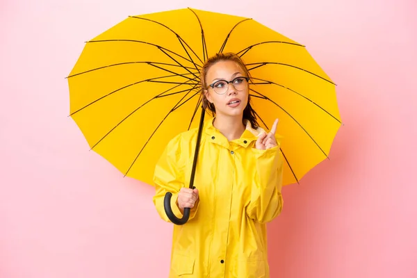 十代のロシアの女の子とともに防水コートと傘隔離された上にピンクの背景考え方指アップ — ストック写真