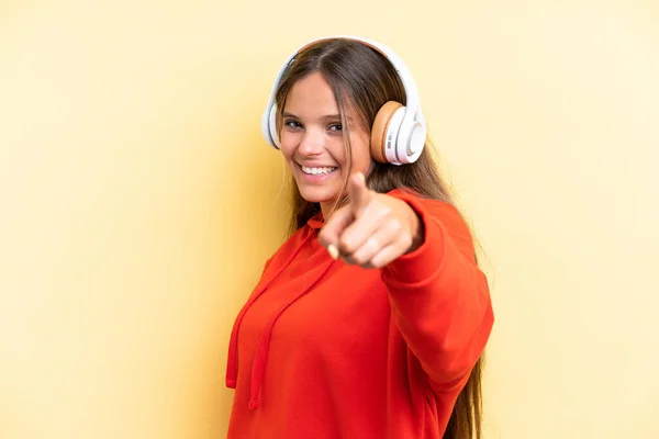 Jovem Caucasiana Isolada Fundo Amarelo Ouvindo Música Apontando Para Frente — Fotografia de Stock