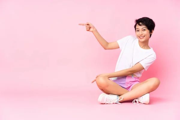 Jovem Vietnamita Com Cabelo Curto Sentado Chão Sobre Fundo Rosa — Fotografia de Stock