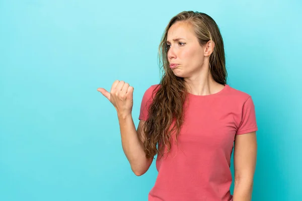 Jonge Kaukasische Vrouw Geïsoleerd Blauwe Achtergrond Ongelukkig Wijzen Naar Zijkant — Stockfoto