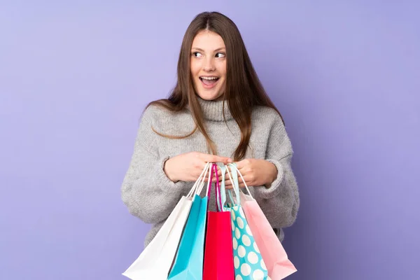 Adolescente Caucásico Chica Aislado Púrpura Fondo Sosteniendo Bolsas Compras Sorprendido — Foto de Stock