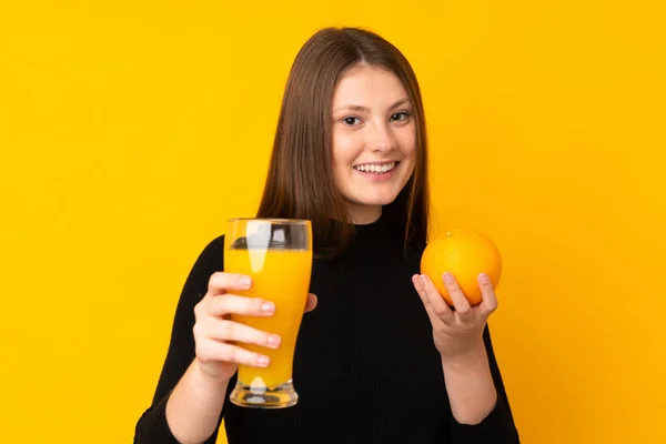 Tonåring Kaukasiska Flicka Som Håller Orange Över Isolerad Gul Bakgrund — Stockfoto