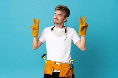 Genç elektrikçi iki eliyle zafer işareti gösteriyor.