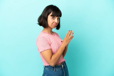 Genç melez kadın mavi arka planda bir şeyler planlıyor.