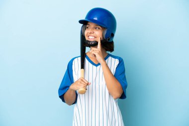Beyzbolcu, miğferli ve beysbol sopalı kadın. Mavi arka planda izole edilmiş, yukarı bakarken bir fikir düşünüyor.