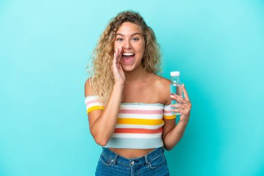 Mavi arka planda su şişesi olan genç sarışın kadın ağzı açık bağırıyor.
