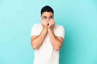 Genç Arap adam mavi arka planda izole edilmiş gergin ve korkmuş bir şekilde elleriyle suni teneffüs yapıyor.