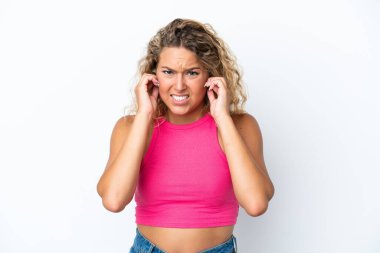 Beyaz arka planda izole edilmiş kıvırcık saçlı kız hayal kırıklığına uğramış ve kulaklarını kapatmış.