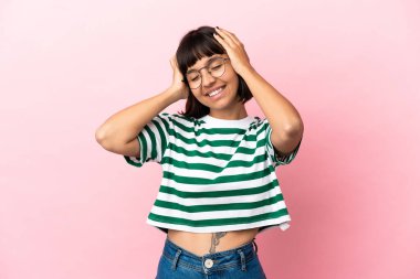 Genç melez kadın pembe arka planda yalnız gülüyor.