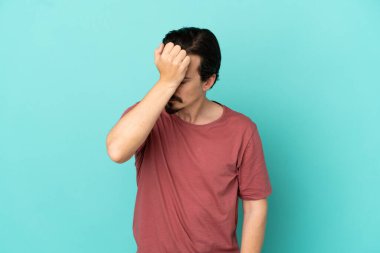 Kafkasyalı genç adam mavi arka planda izole edilmiş, baş ağrısı var.