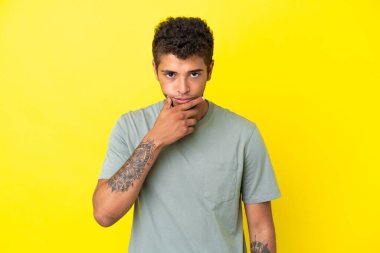 Genç yakışıklı Brezilyalı adam sarı arka planda izole edilmiş.