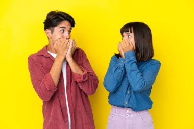 Sarı arka planda izole edilmiş genç melez çift biraz gergin ve korkmuş durumda.