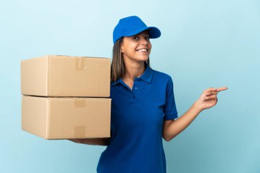 Genç teslimatçı kadın mavi arka planda izole edilmiş.