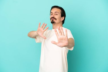 Kafkasyalı genç adam mavi arka planda izole edilmiş gergin eller öne doğru uzanıyor.