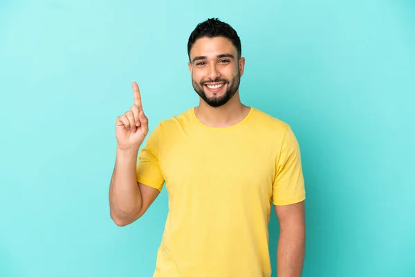 Hombre Árabe Joven Aislado Sobre Fondo Azul Mostrando Levantando Dedo — Foto de Stock