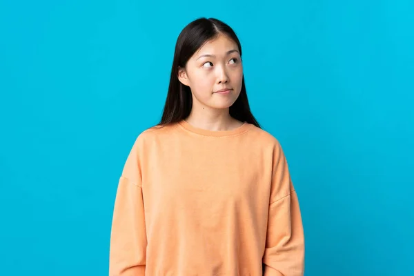 Menina Chinesa Jovem Sobre Fundo Azul Isolado Com Dúvidas Olhar — Fotografia de Stock
