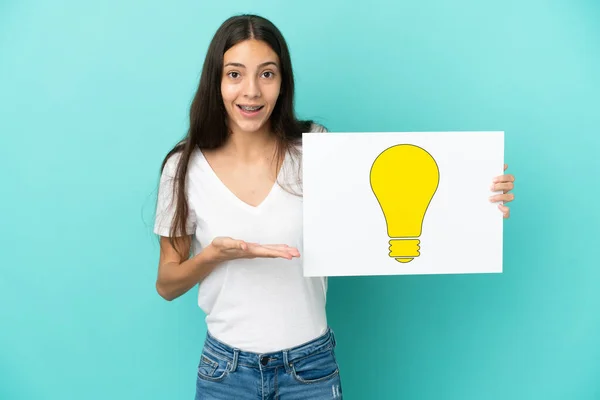 Young French Woman Isolated Blue Background Holding Placard Bulb Icon — Stock Photo, Image