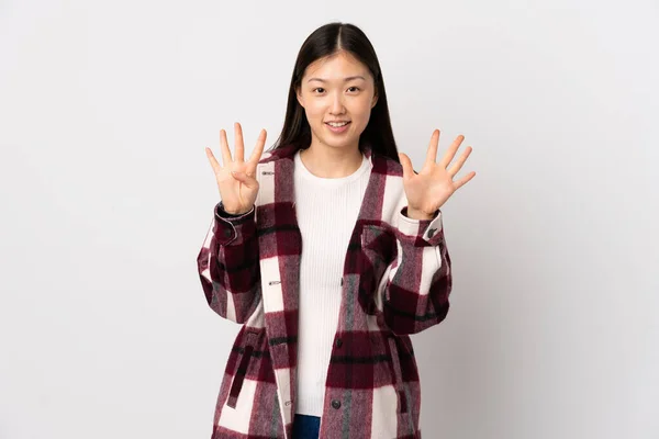 年轻的中国女孩在孤独的白种人背景上 用手指数着9 — 图库照片