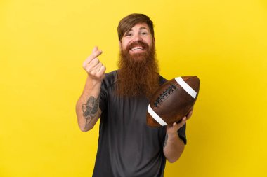 Kızıl saçlı beyaz adam sarı arka planda ragbi oynuyor. 