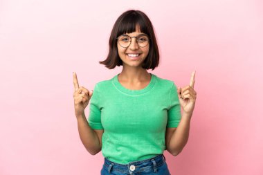 Pembe arka planda izole edilmiş genç melez kadın harika bir fikre işaret ediyor.