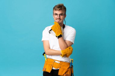 Genç elektrikçi, gözlüklü ve gülümseyen izole duvarın üzerinde.